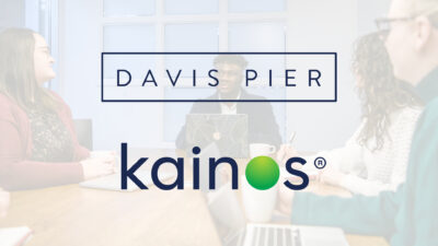 Davis Pier and Kainos logos over a faded photo of the Davis Pier team meeting in one of our conference rooms.