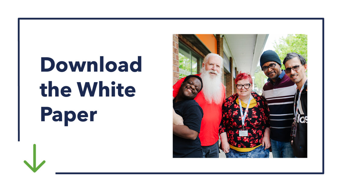 Promotional graphic that reads "Download the White Paper" with a downward arrow indicating the photo is linked. There is a photo of four people smiling together alongside the text.