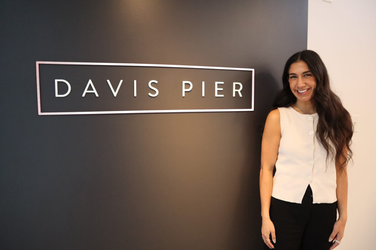 A portrait-style photo of Nalini standing beside a Davis Pier sign near the reception area of our Halifax office.